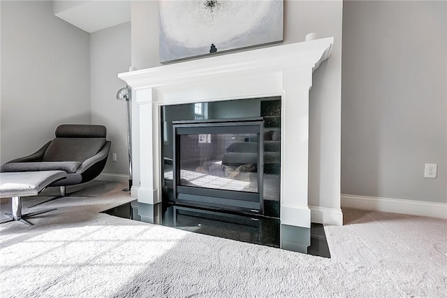 interior details with a glass covered fireplace, baseboards, and carpet