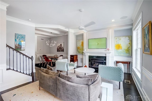 living area with stairway, wood finished floors, visible vents, a glass covered fireplace, and crown molding