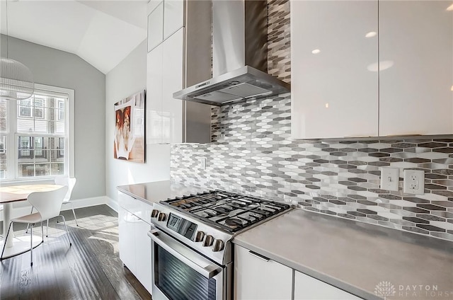 kitchen with lofted ceiling, stainless steel range with gas stovetop, white cabinets, wall chimney exhaust hood, and backsplash