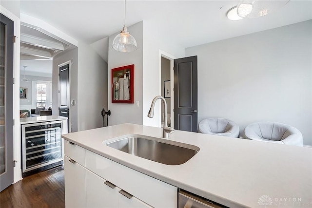 kitchen with light countertops, white cabinets, beverage cooler, and a sink