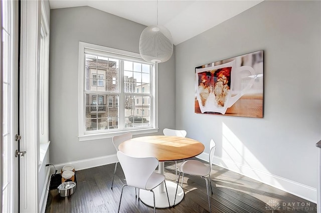 dining space featuring baseboards, wood finished floors, and vaulted ceiling