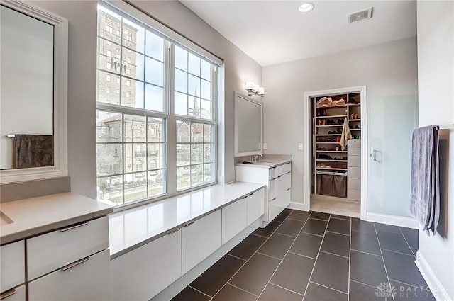 bathroom with a spacious closet, visible vents, baseboards, recessed lighting, and vanity