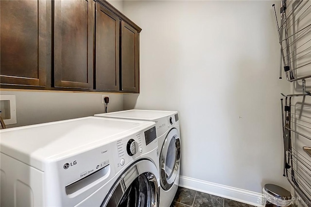 clothes washing area with cabinet space, washing machine and dryer, and baseboards