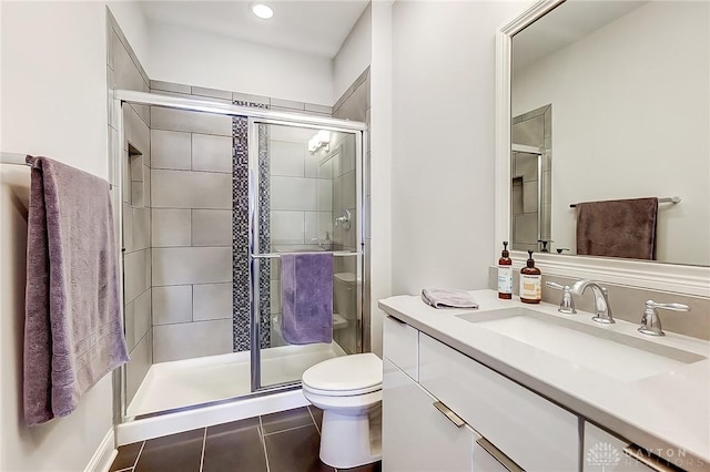 bathroom featuring tile patterned floors, a stall shower, toilet, and vanity