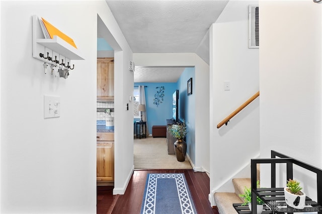 hallway with visible vents, a textured ceiling, dark wood finished floors, stairway, and baseboards