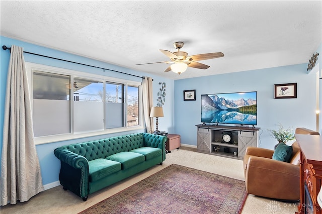 carpeted living room featuring baseboards, a textured ceiling, and a ceiling fan