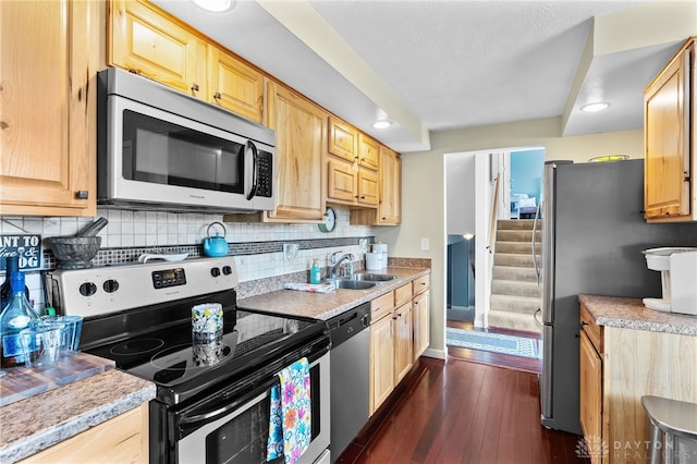 kitchen with a sink, tasteful backsplash, dark wood-style floors, appliances with stainless steel finishes, and light countertops