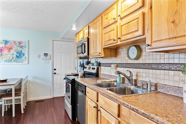 kitchen featuring baseboards, a sink, stainless steel appliances, dark wood-type flooring, and backsplash