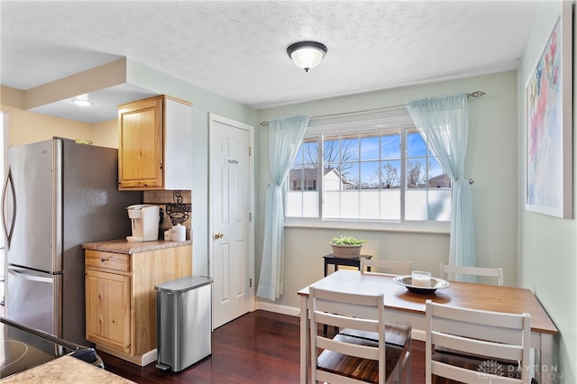 kitchen featuring light brown cabinetry, a textured ceiling, freestanding refrigerator, and dark wood-style flooring