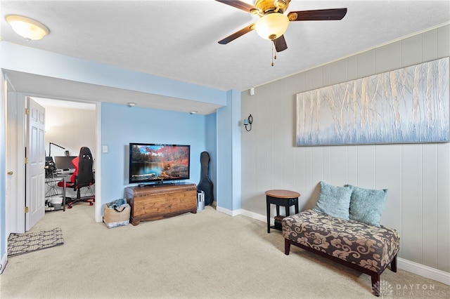 living area featuring carpet, baseboards, and ceiling fan