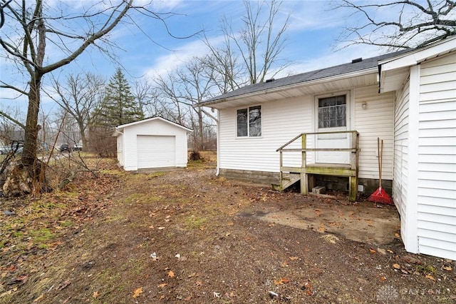 view of yard featuring a detached garage, an outdoor structure, and dirt driveway