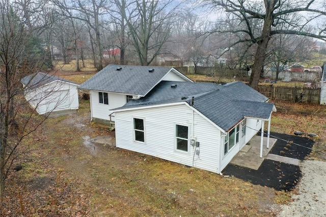 exterior space with an outbuilding, fence, and a shingled roof