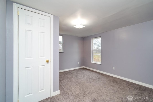 carpeted spare room featuring baseboards