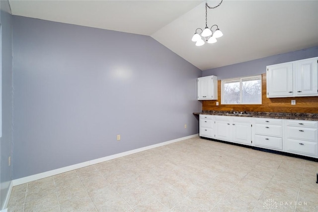 kitchen featuring baseboards, lofted ceiling, tasteful backsplash, and white cabinetry