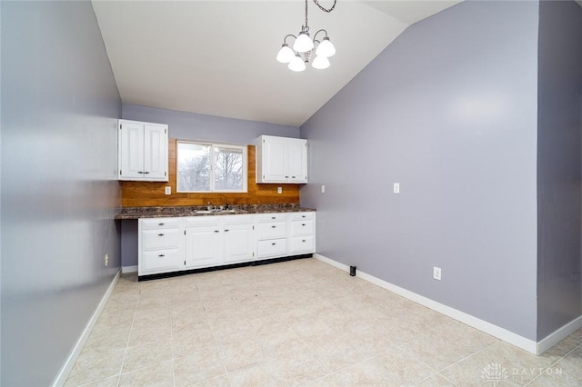 kitchen with white cabinetry, lofted ceiling, baseboards, and a sink