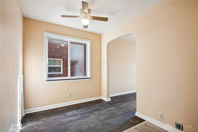 unfurnished room featuring ceiling fan, baseboards, arched walkways, and wood finished floors