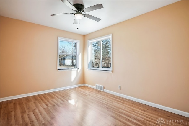 spare room with wood finished floors, baseboards, visible vents, and ceiling fan