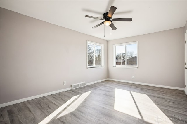 spare room featuring a ceiling fan, wood finished floors, baseboards, and visible vents