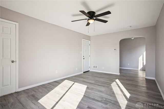 spare room featuring visible vents, ceiling fan, baseboards, wood finished floors, and arched walkways