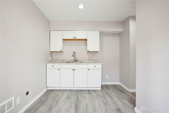 kitchen featuring light countertops, baseboards, visible vents, and a sink