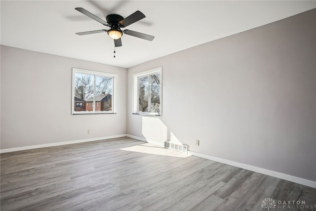 unfurnished room with ceiling fan, wood finished floors, visible vents, and baseboards