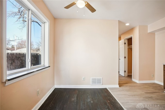 empty room with wood finished floors, baseboards, and visible vents