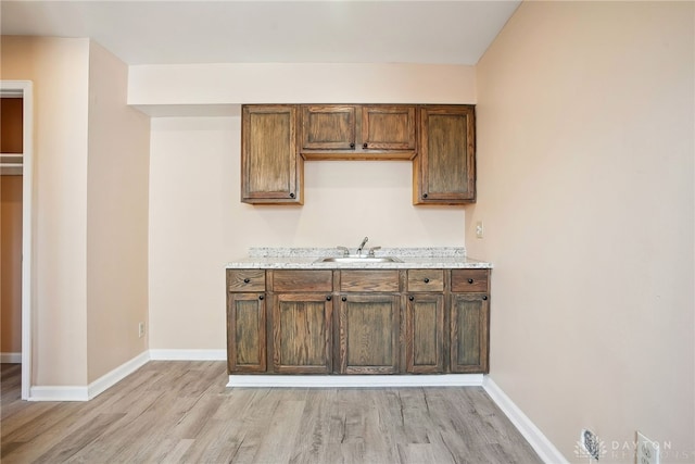 kitchen featuring light wood-style flooring, baseboards, and a sink