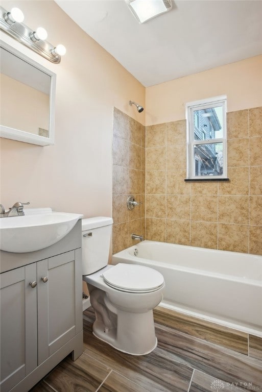 full bathroom with wood finished floors, toilet, vanity, and washtub / shower combination