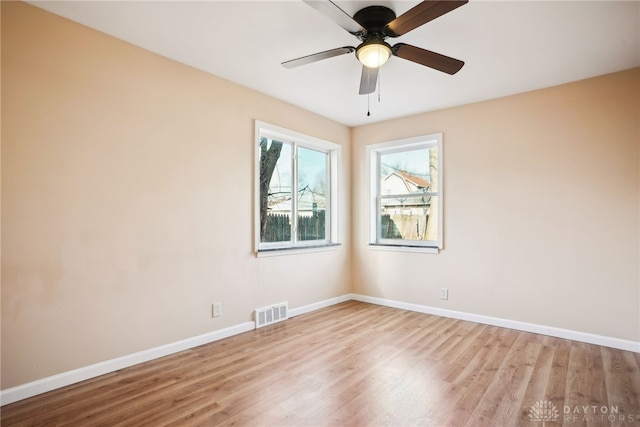 unfurnished room with visible vents, light wood-style flooring, a ceiling fan, and baseboards