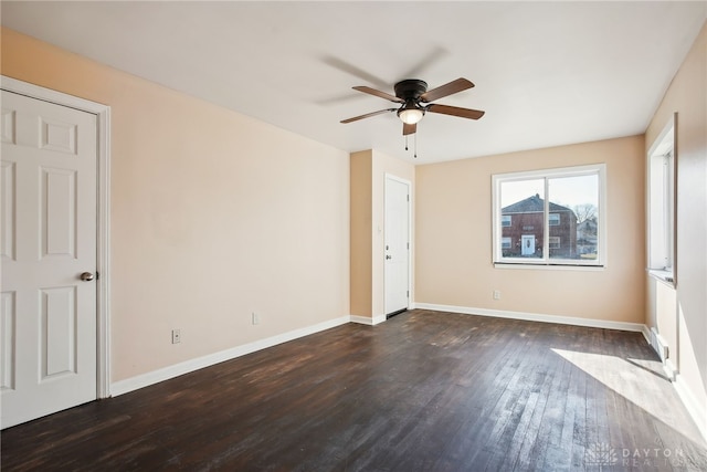 empty room with baseboards, dark wood finished floors, and a ceiling fan