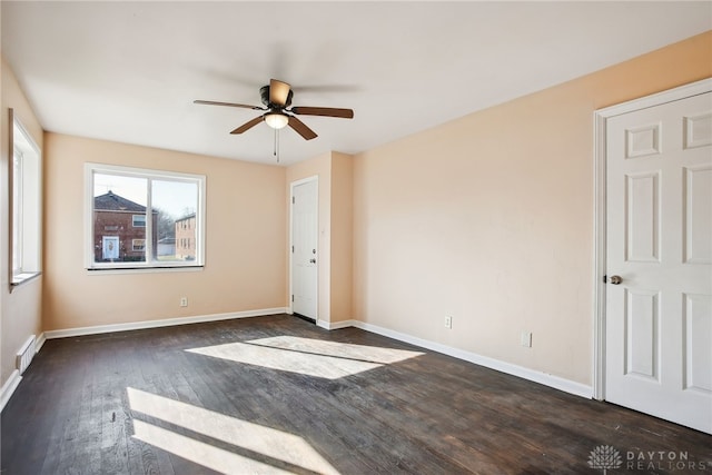 spare room featuring visible vents, ceiling fan, dark wood-type flooring, and baseboards