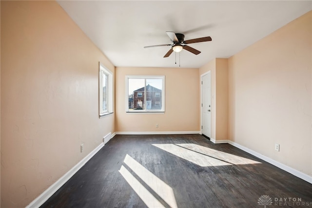 unfurnished room with dark wood finished floors, visible vents, baseboards, and a ceiling fan