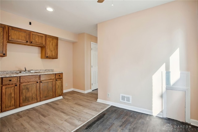 kitchen featuring a sink, visible vents, brown cabinets, and wood finished floors