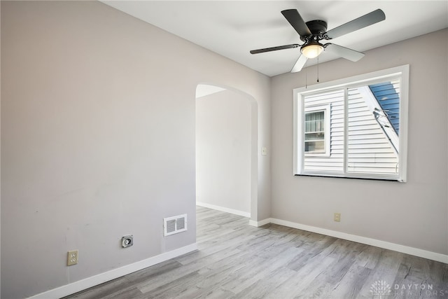 spare room with wood finished floors, baseboards, visible vents, and arched walkways