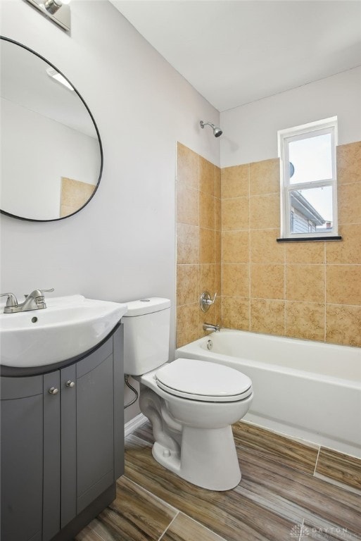 full bath with washtub / shower combination, toilet, wood finished floors, and vanity