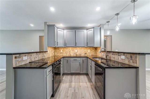 kitchen featuring a peninsula, black appliances, gray cabinetry, and a sink