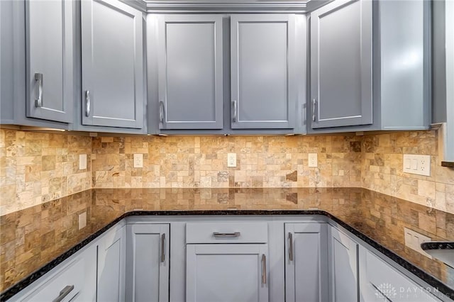 kitchen with tasteful backsplash, gray cabinets, and dark stone countertops