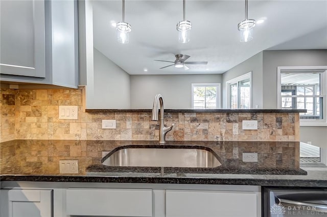 kitchen with a sink, dark stone counters, decorative backsplash, and white cabinetry