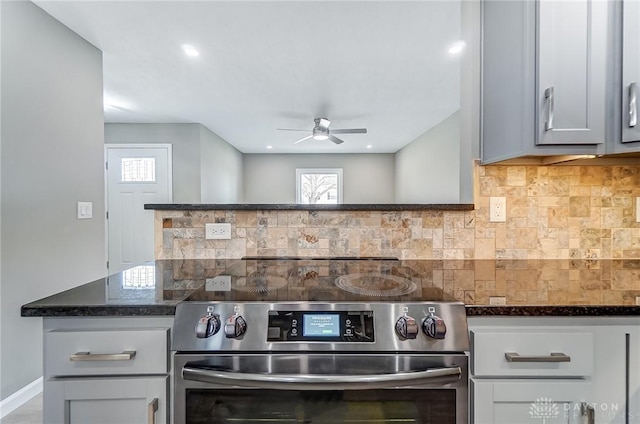 kitchen with a ceiling fan, baseboards, dark stone counters, stainless steel range with electric cooktop, and backsplash