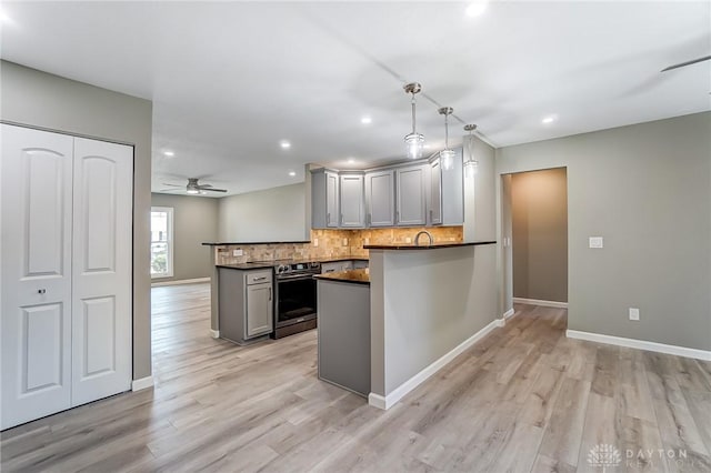 kitchen with gray cabinetry, tasteful backsplash, dark countertops, a peninsula, and stainless steel electric range oven