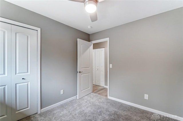 unfurnished bedroom with a closet, baseboards, light colored carpet, and a ceiling fan