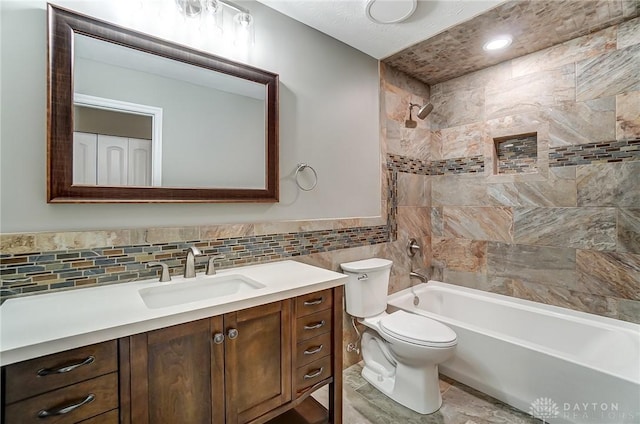 full bath with toilet, shower / bathing tub combination, tile walls, wainscoting, and vanity