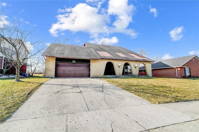 view of front of home featuring a front yard, concrete driveway, brick siding, and a garage