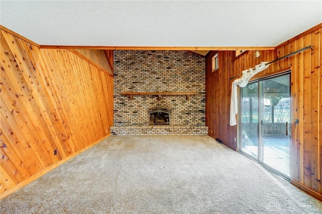 unfurnished living room featuring a brick fireplace, carpet flooring, and wood walls