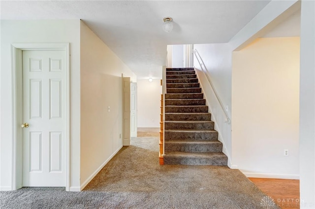 staircase with baseboards and carpet floors