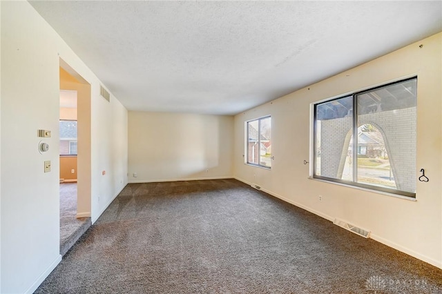 unfurnished room featuring baseboards, visible vents, carpet floors, and a textured ceiling