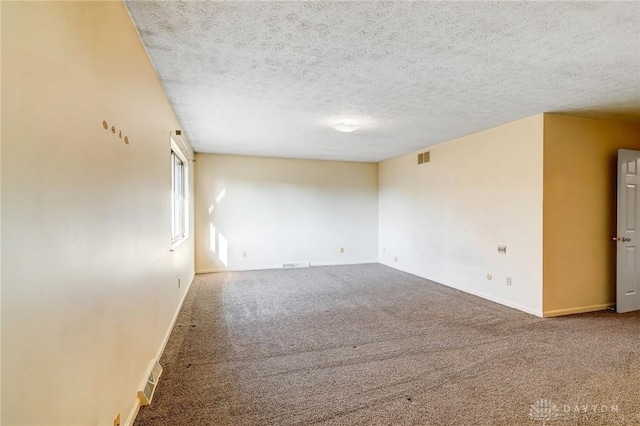 carpeted spare room featuring visible vents, a textured ceiling, and baseboards