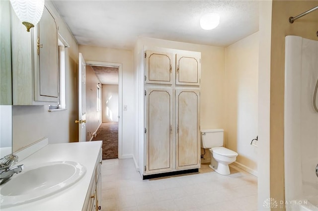 bathroom featuring vanity, toilet, a shower, and baseboards