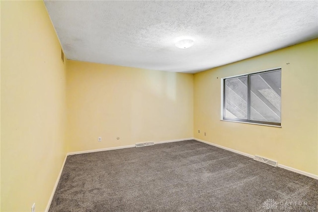 carpeted spare room with visible vents, baseboards, and a textured ceiling