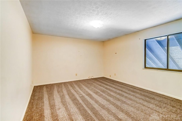 unfurnished room with carpet flooring, baseboards, and a textured ceiling